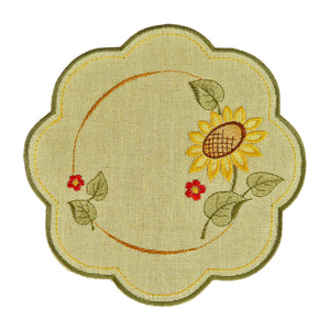 Round sand color table linen with scalloped edges, and a design of a sunflower with leaves and small flowers.