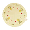 Round white table linen with scalloped edges, and a border of primrose flowers and daisies with ladybugs around it.