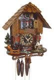 1-Day Schneider Black Forest Chalet Coocoo clock with music. A man is chopping wood on the right side of the platform. On the left, a water wheel spins, and a little brook lined with pebbles on each side is flowing across. There is an evergreen tree and a grazing deer on the left. The clear faced dial shows the sophisticated mechanical movement inside the clock box. Dancers spin on the balcony, above it is the cuckoo clock door underneath the roof with wooden shingles.