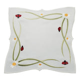 Square white table linen with a border design of ladybugs, daisies, and intertwining stems.
