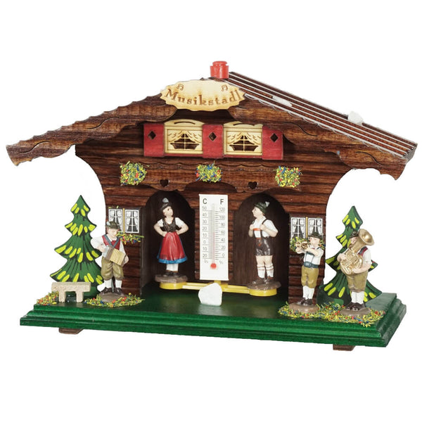 Weather house with brass band to the right and left of the Bavarian couple. There are 3 traditional musical instruments on display, which also play an important role at the Oktoberfest. An accordion, a trumpet and a tuba. A thermometer hangs between the couple. 