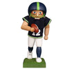 Football Nutcracker in blue green jersey with white pants. He holds the ball in his hand and runs across the field with a purposeful look.