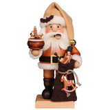 Christian Ulbricht Santa Claus Smoker in subtle brown colors. As decoration he has a holly on the fur edge of his hat and a dark belt around the coat. In one hand he holds a beautiful music box from the Erzgebirge and in the other a burlap sack with presents. If you look closely you can see a children's spinning top and a small nutcracker peeping out of the bag. A small rocking horse ornament is attached to the string with which the gift pouch is tied shut.  