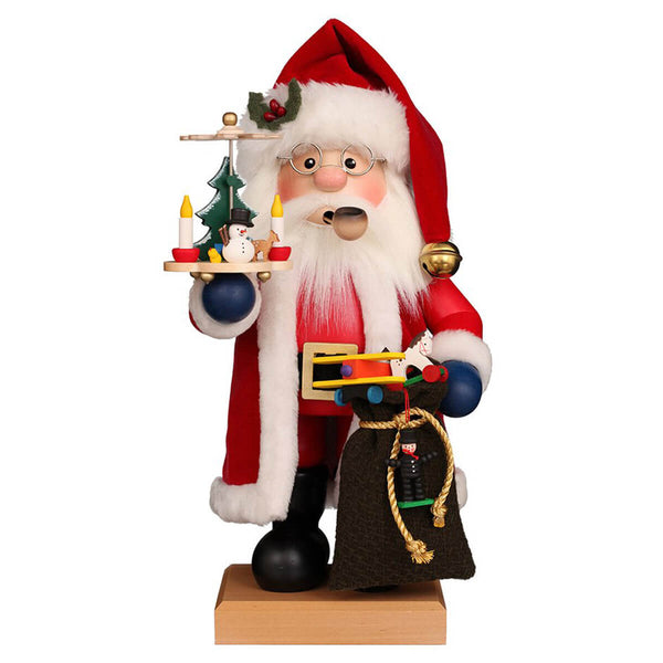 Christian Ulbricht Santa Claus Smoker in traditional red coat with white fur trim and matching hat, ready to distribute his gifts. In one hand he holds his gift bag with a small chimney sweep ornament from which an airplane is peeking out and in the other hand a Christmas pyramid.
