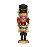 This stunning hand carved nutcracker is dressed in the fine attire of a marching band drummer. His outfit features a large black marching band, a red jacket and belt with golden accents, light yellow pants and tall black boots. This drummer holds his sticks and his drum at the ready